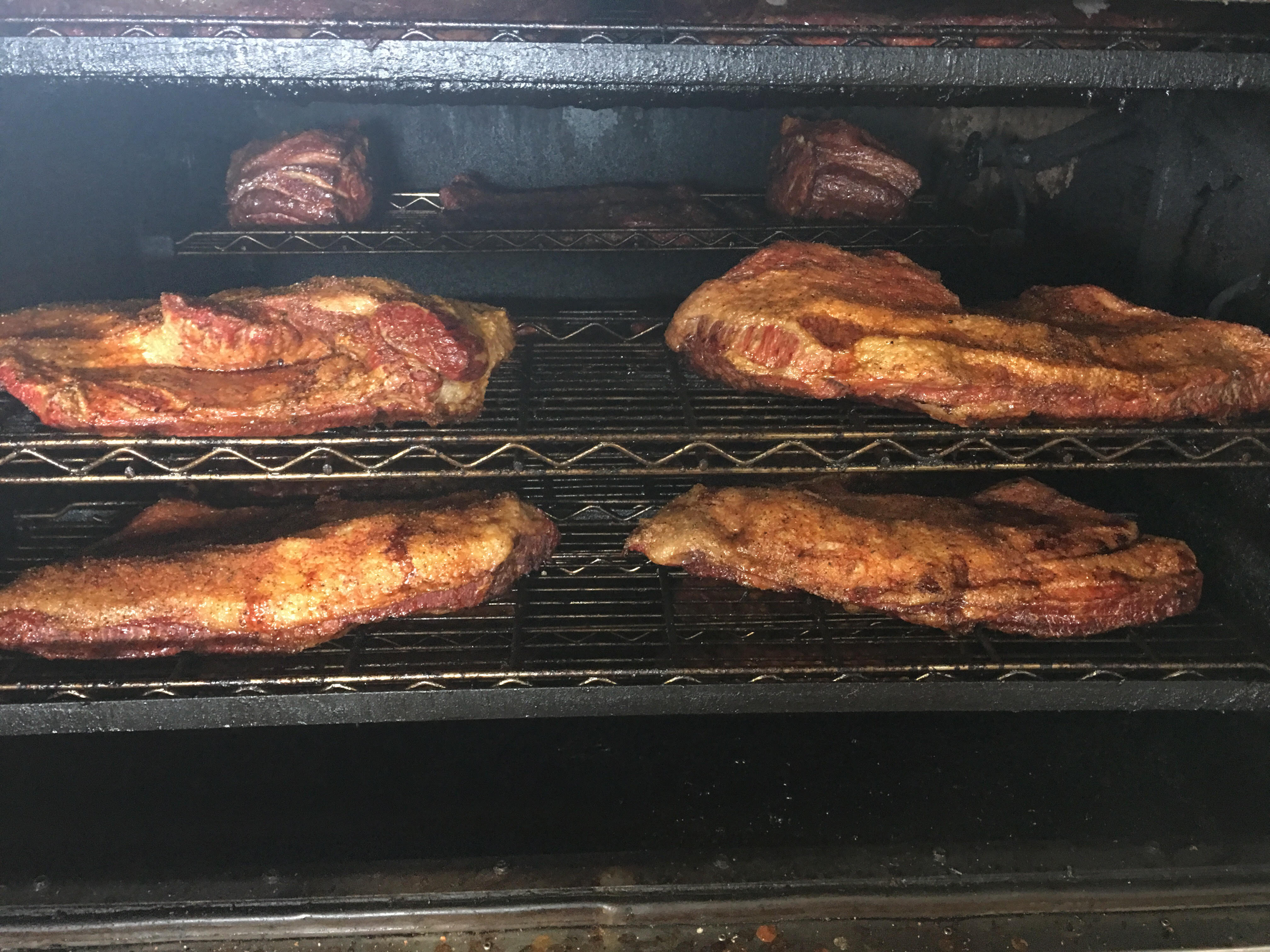 Beef cuts smoking low and slow on the racks inside R & R BBQ's mesquite smoker in Stephenville, TX